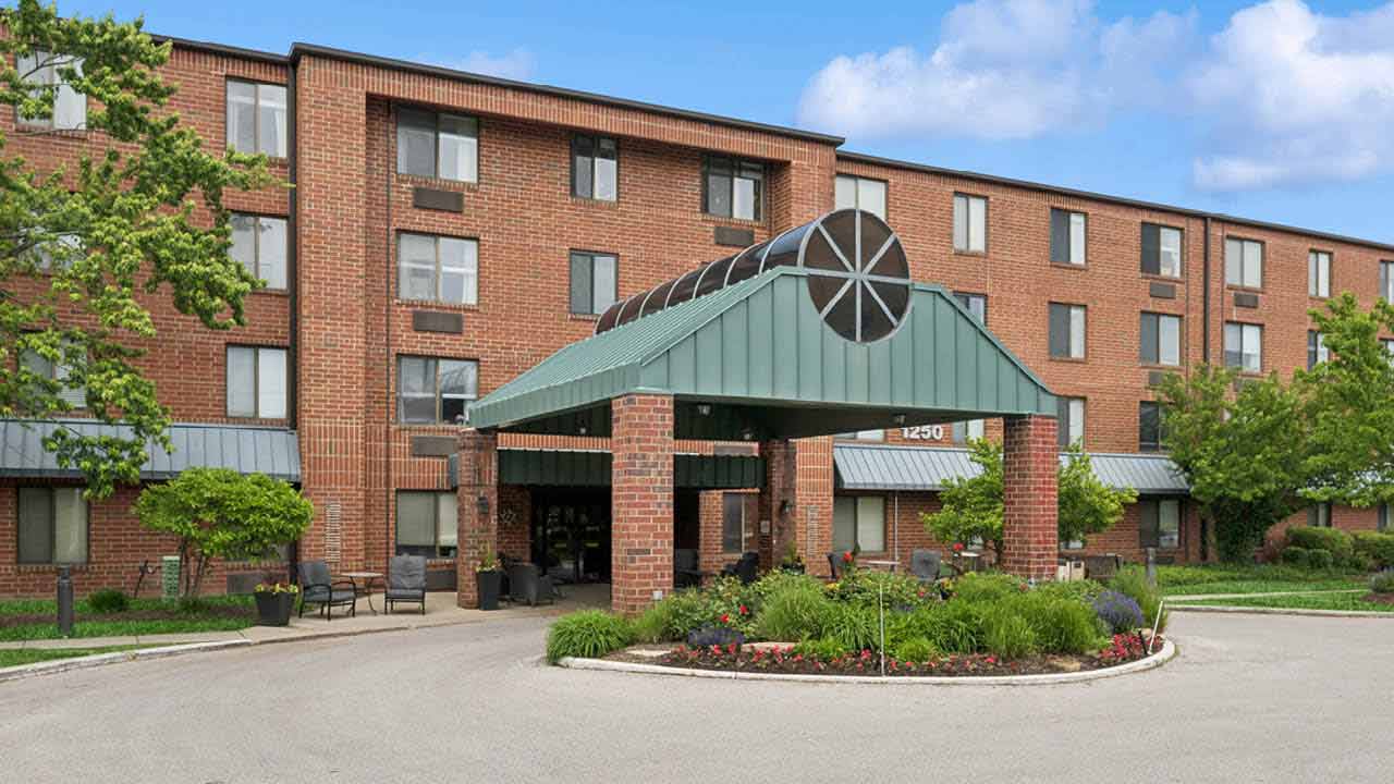 Multi-story brick senior living building with a green canopy at Church Creek in Arlington Heights, IL, Cook County.