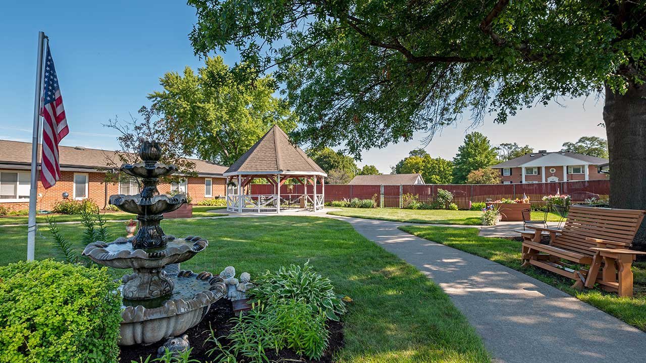 White gazebo and garden with a paved walking path at Fair Oaks Rehabilitation in South Beloit, IL, Winnebago County.
