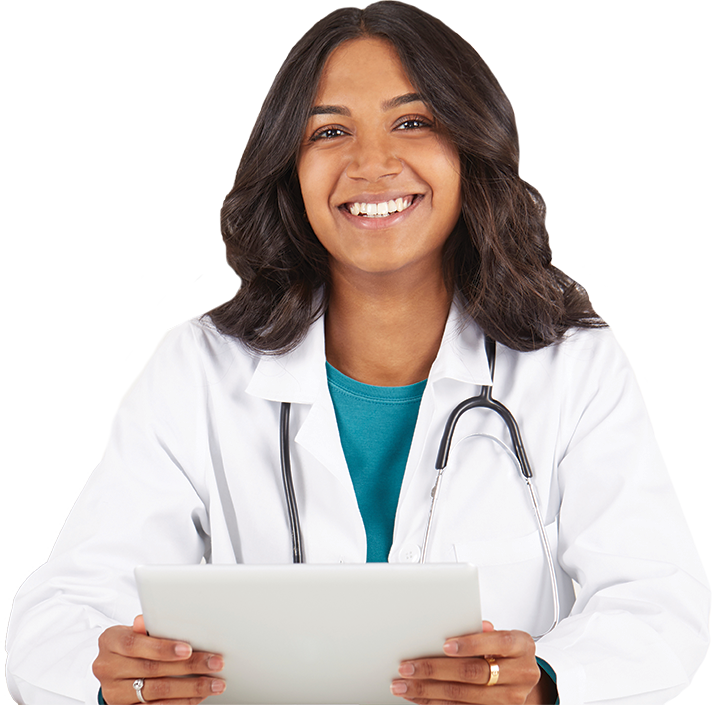 A smiling woman with shoulder-length dark hair, wearing a white lab coat and a stethoscope around her neck, sits at a desk holding a tablet. She appears to be reviewing information on long-term care.
